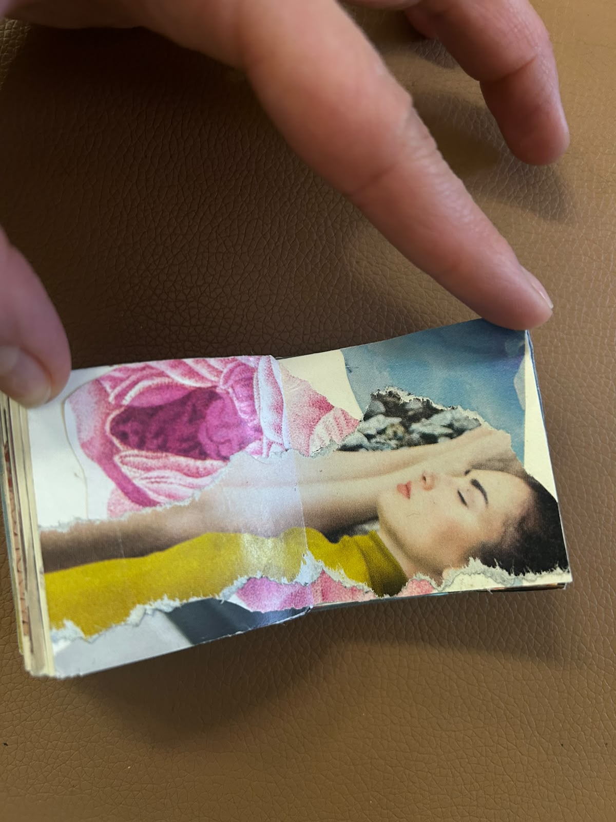 Handmade collage book opened to a reclining portrait among pink and yellow paper